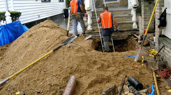 Contractors performing foundation protection and exterior drainage excavation near residential home steps in Erie, PA
